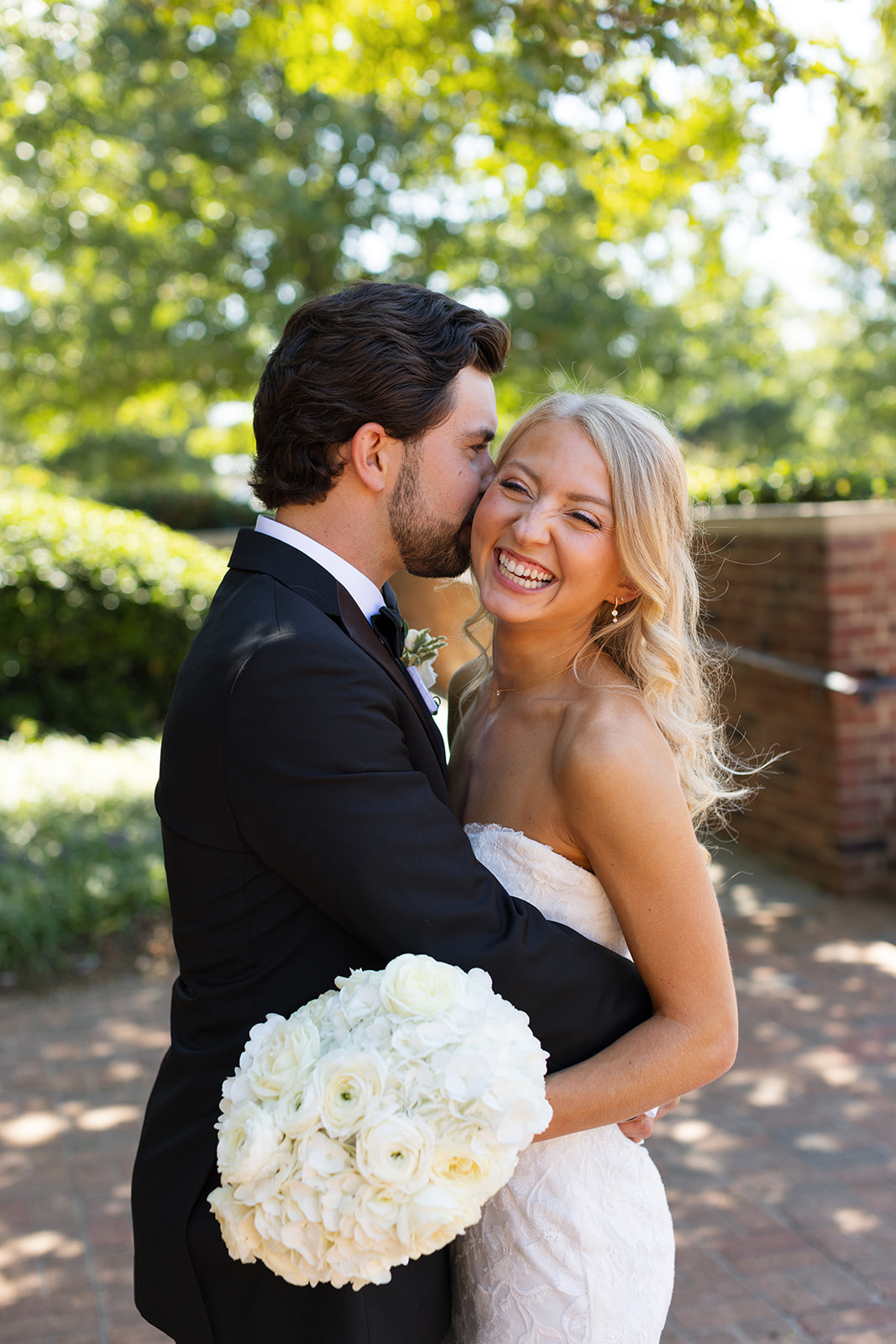 groom kissing the bride on the cheek in a timeless wedding photo a moment taken during their wedding weekend timeline