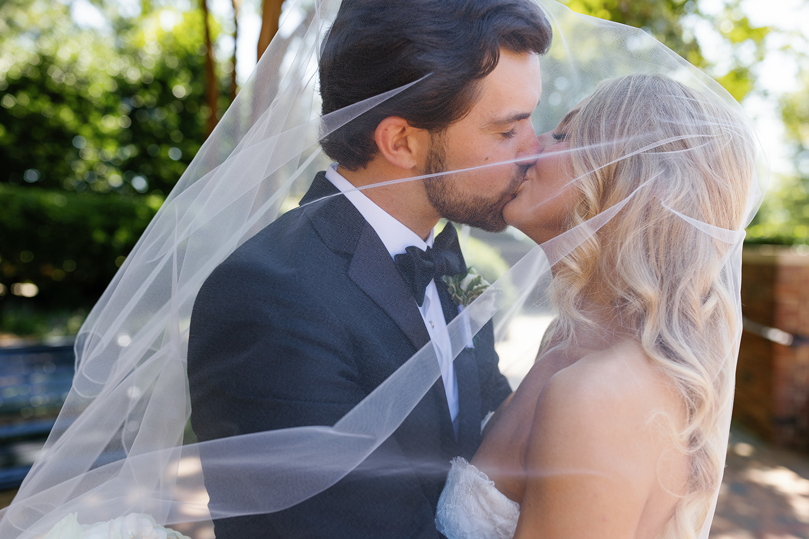bride and groom kissing under her veil in greenville a moment taken during their wedding weekend timeline