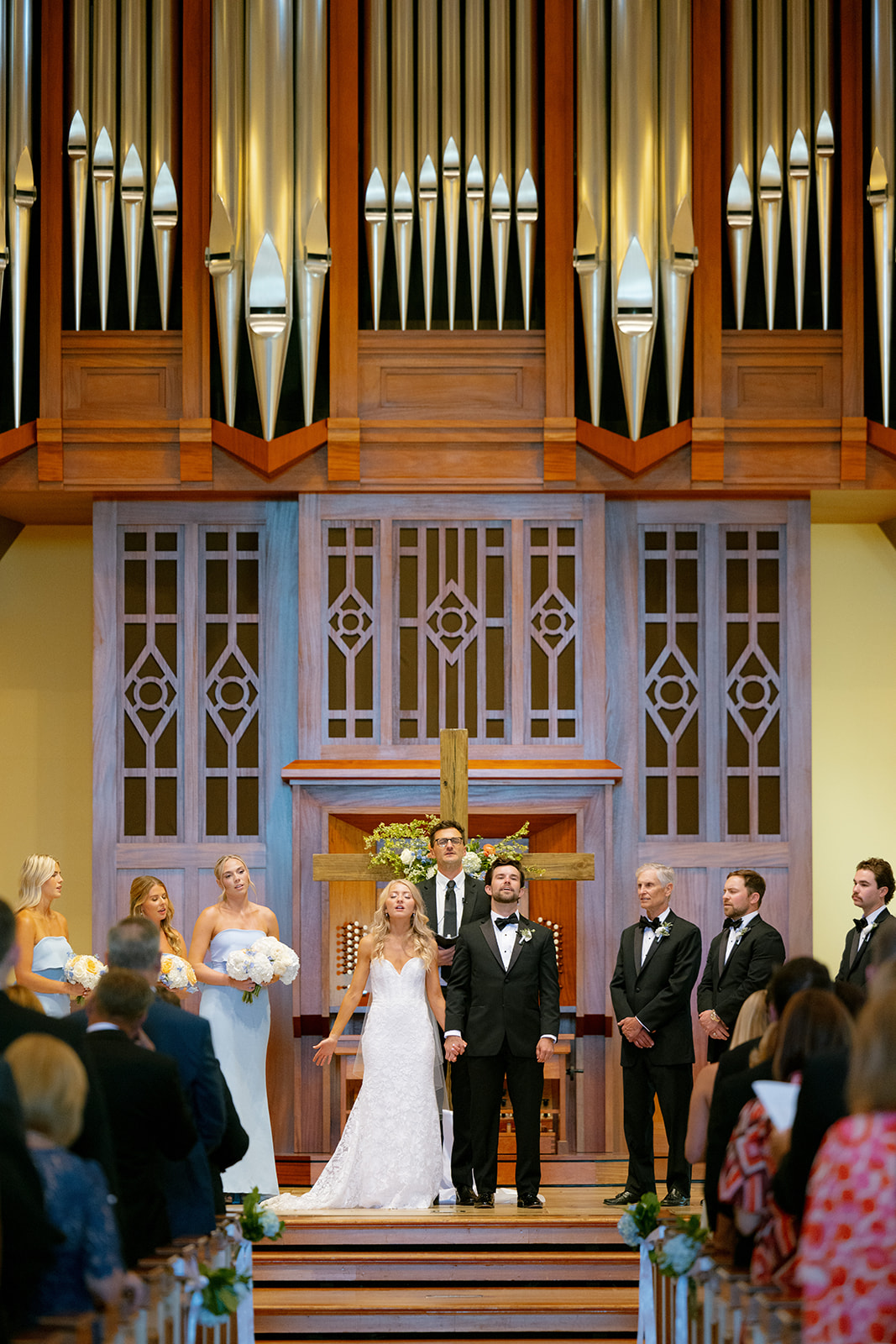 The couple bows their heads in prayer during their ceremony, a meaningful tradition in their wedding weekend timeline.