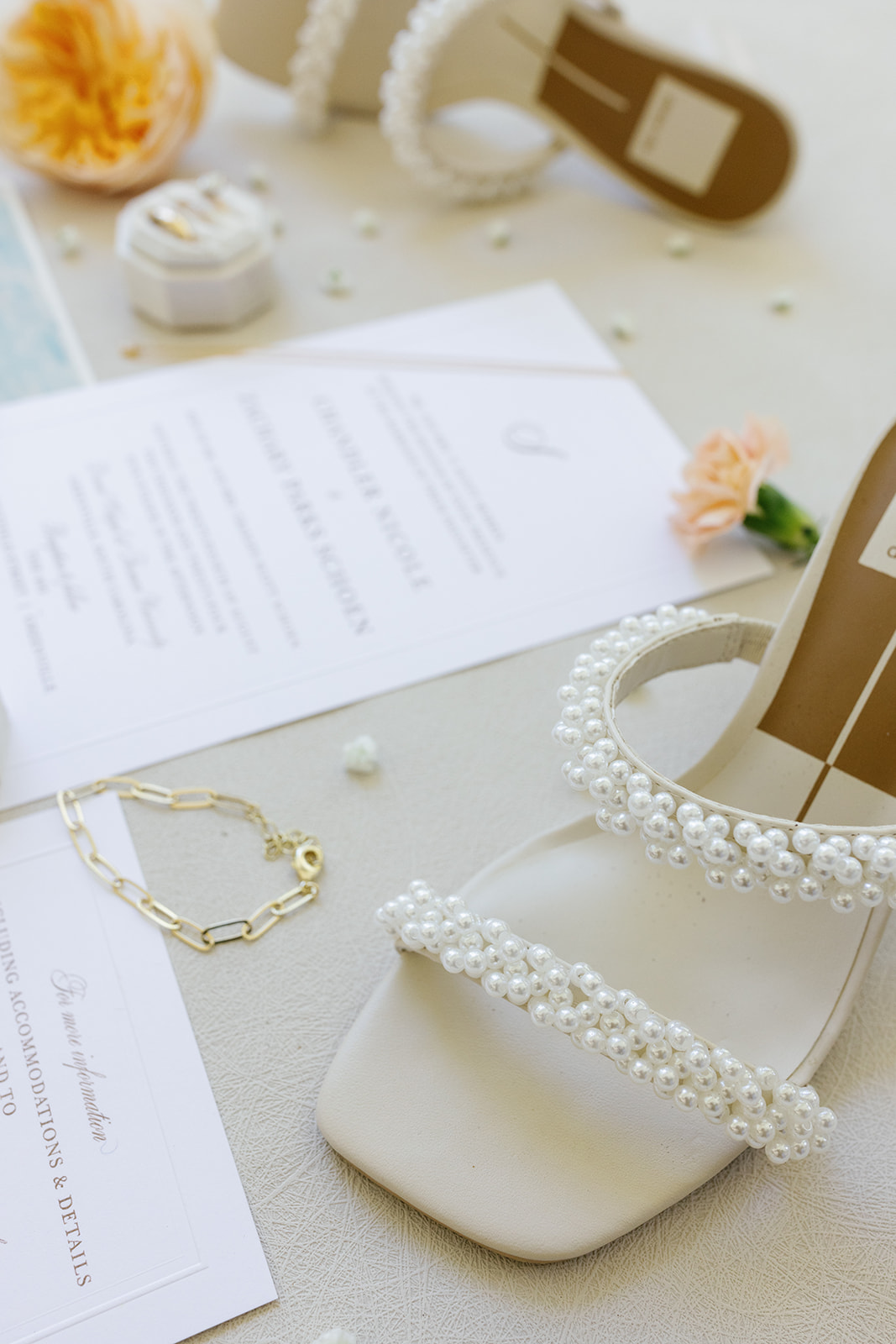 Bridal details featuring pearl-embellished wedding shoes, gold bracelet, and wedding invitations, styled with soft florals for a timeless Greenville, SC wedding