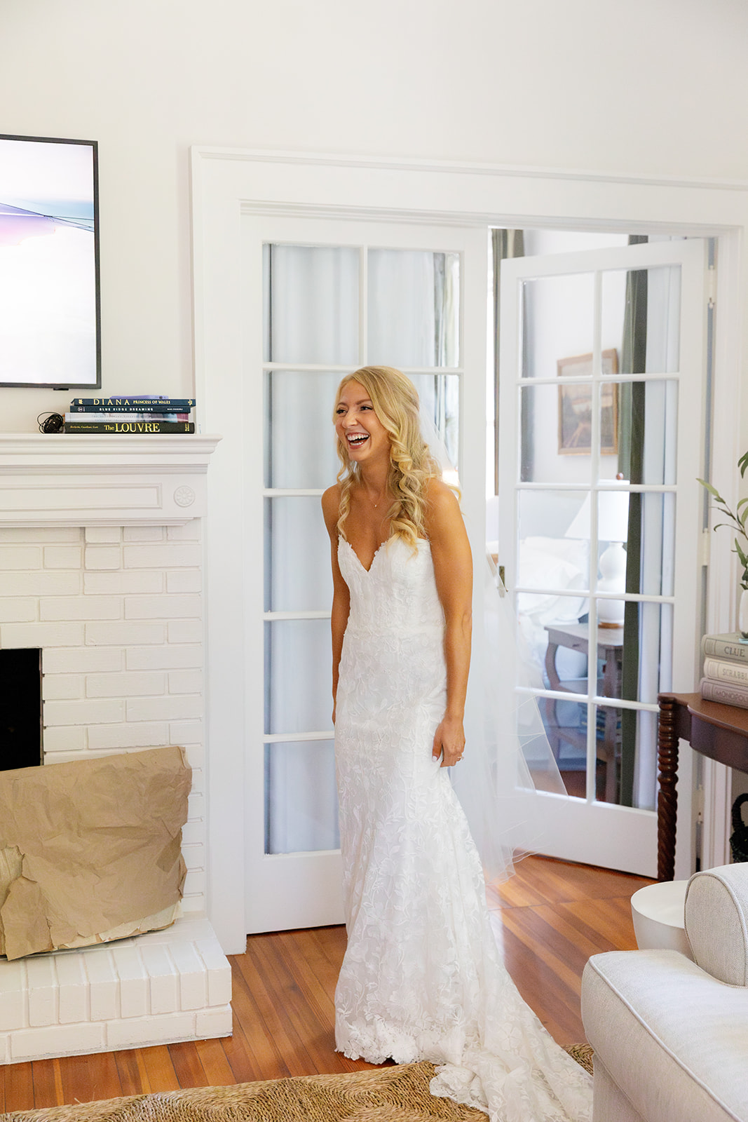 Bride laughing as she walks into the room for her bridesmaids' first look at a Greenville, SC Airbnb.