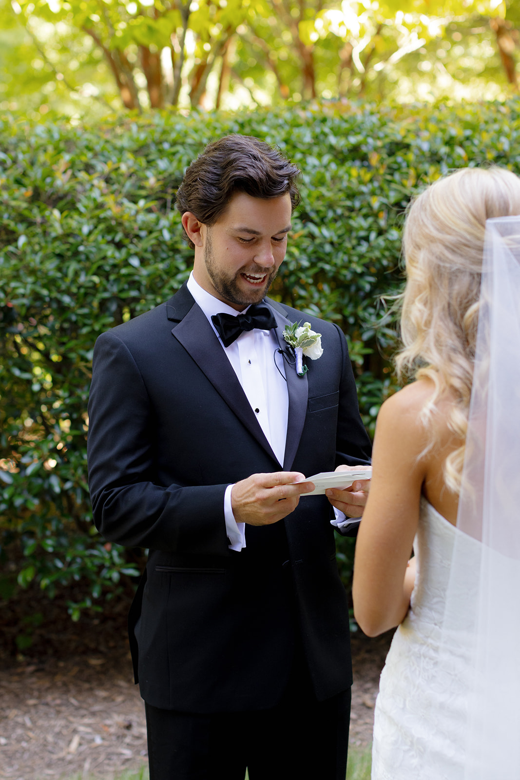 Groom smiles while reading his vows to the bride in a garden setting in Greenville.