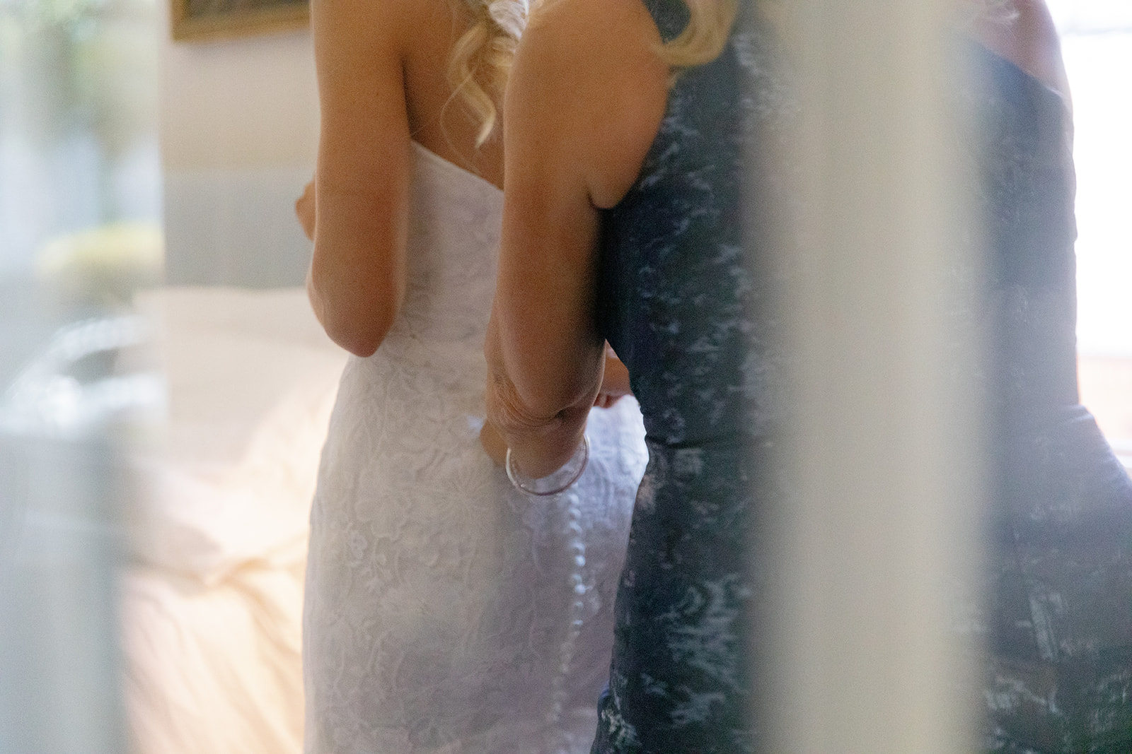 Bride’s mother adjusting the back of her wedding dress in an intimate pre-ceremony moment.
