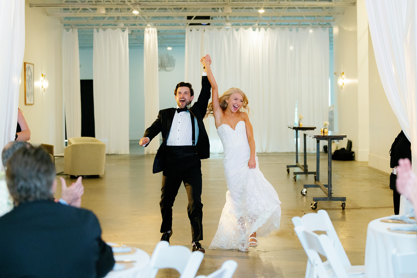 Bride and groom holding hands, soaking in the joy of their wedding celebration.