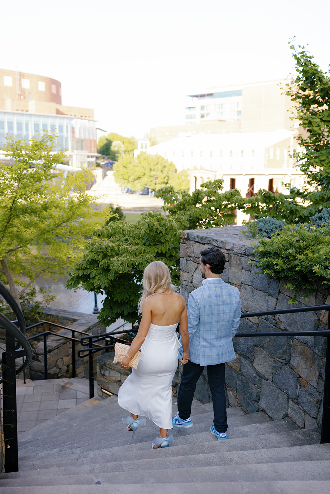 Bride and groom holding hands while walking down stone steps in Greenville, SC during their wedding weekend