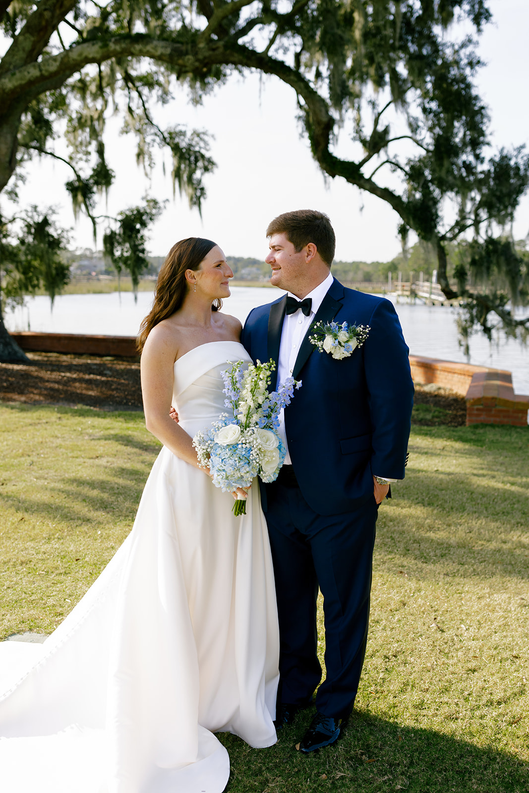 Mills and Brooks smile at each other under a mossy oak by the water in Charleston, SC.