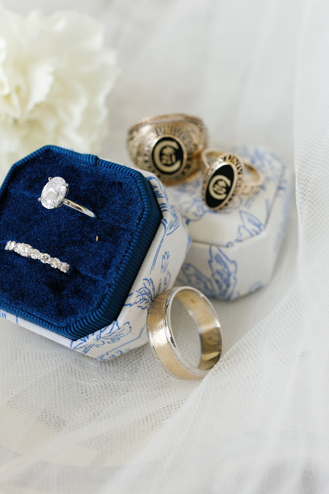 Close-up of the bride and groom’s wedding bands and engagement ring styled with Clemson rings.