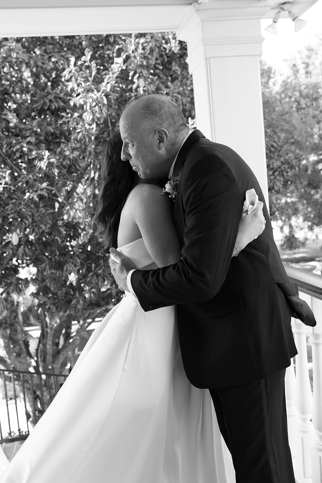 Bride Mills hugs her father tightly during their emotional first look on a veranda in Charleston, SC.