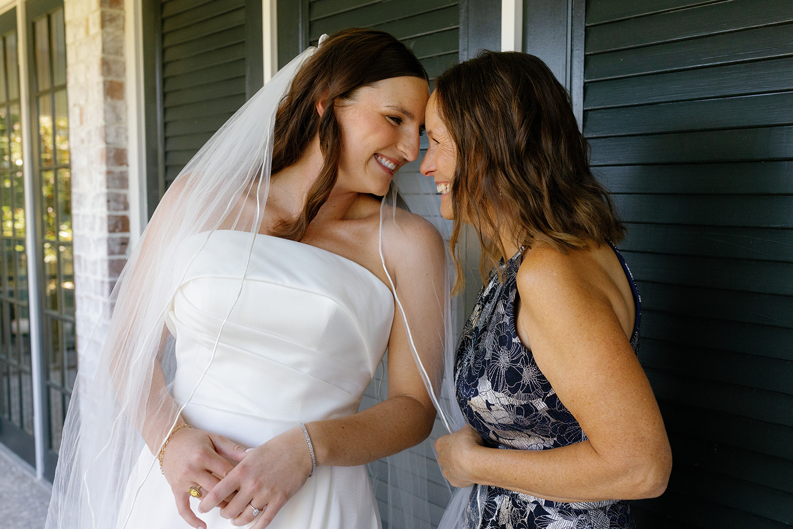 Bride Mills and her mom share a joyful forehead-to-forehead moment before the ceremony.