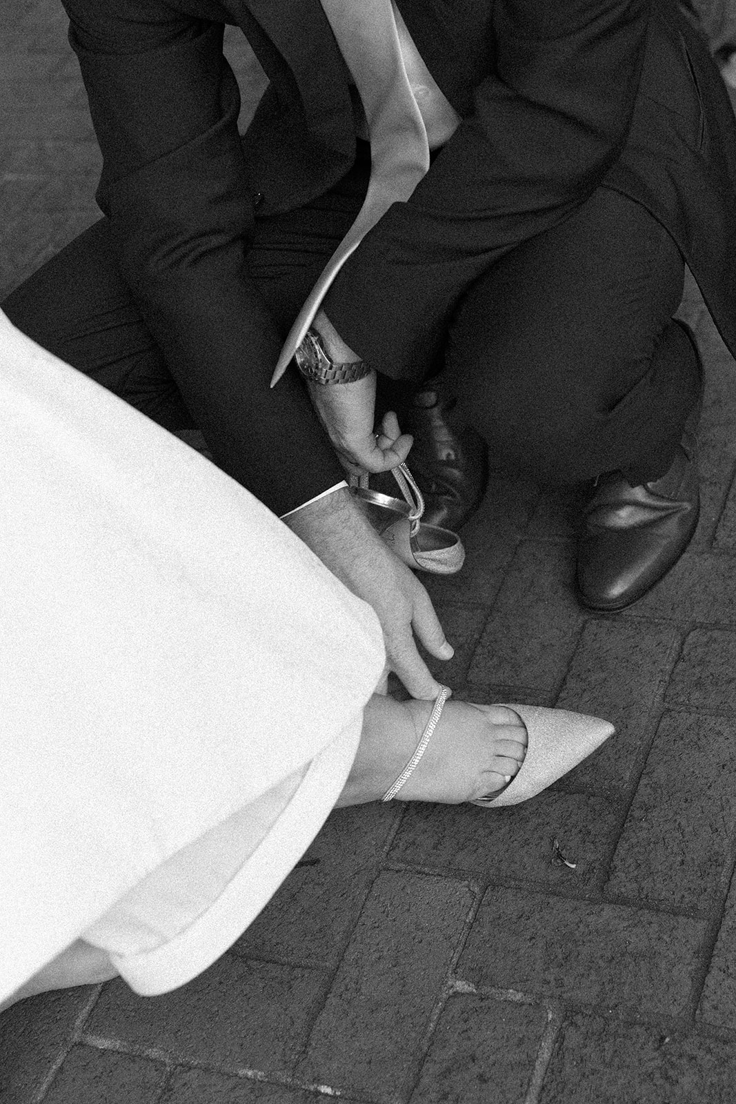 groom helping the bride put on her shoe