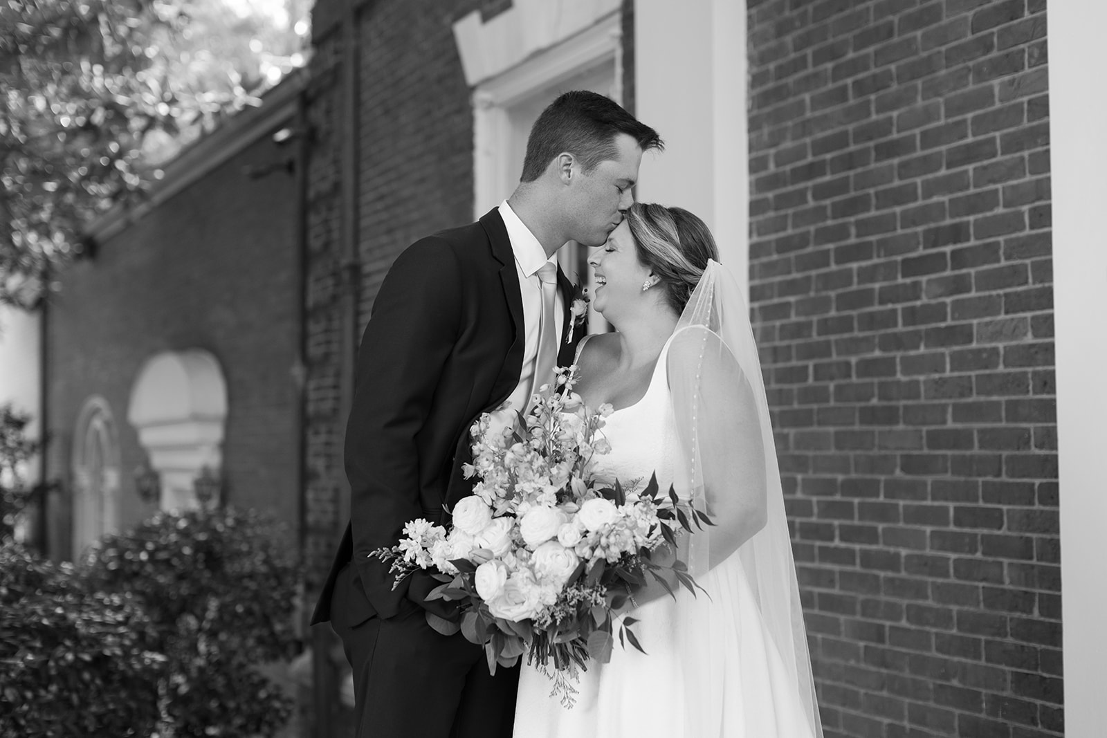 groom kisses bride on forehead outside their wedding venue