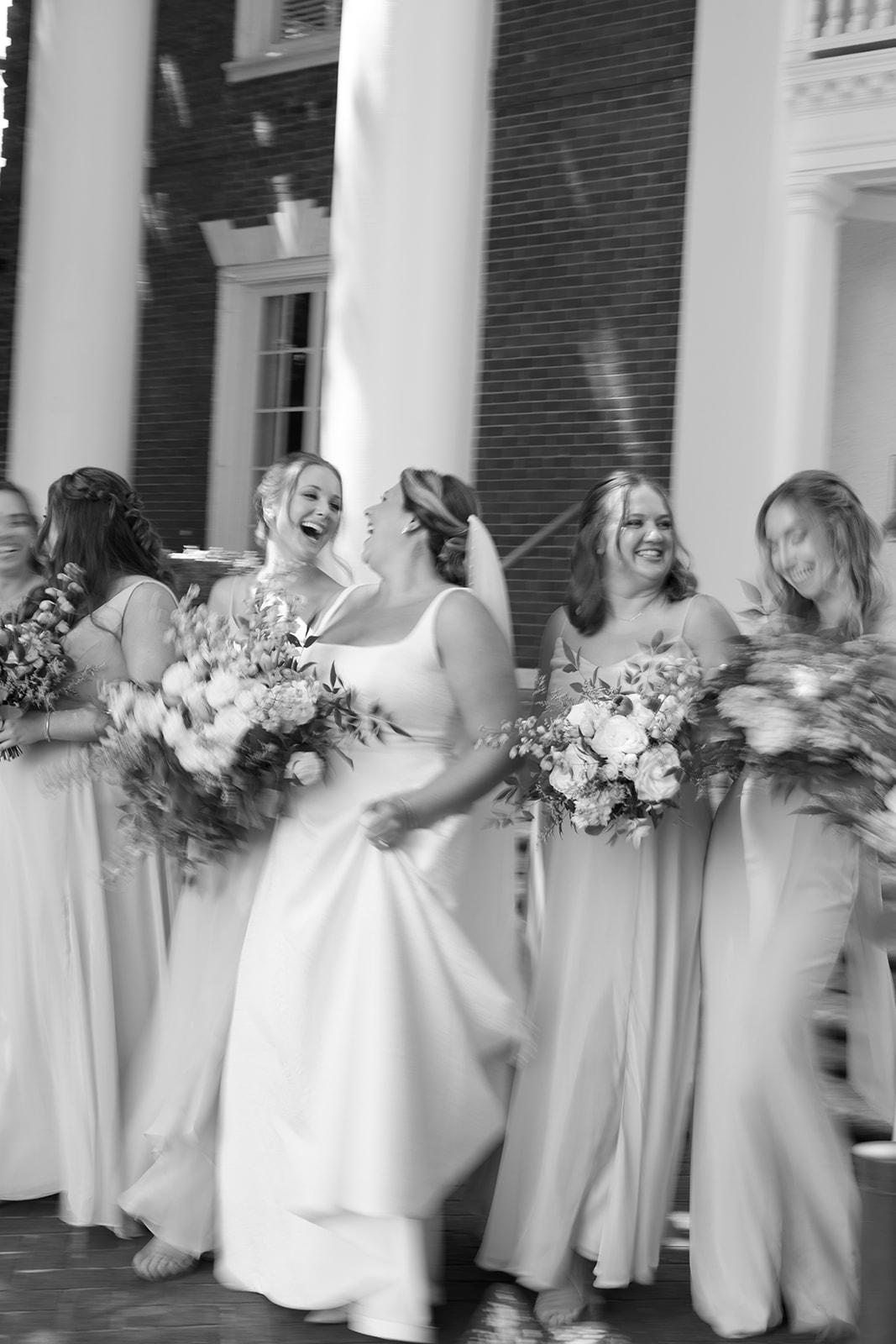 bride and bridal party laughing together as a Greenville wedding photographer takes their photo 