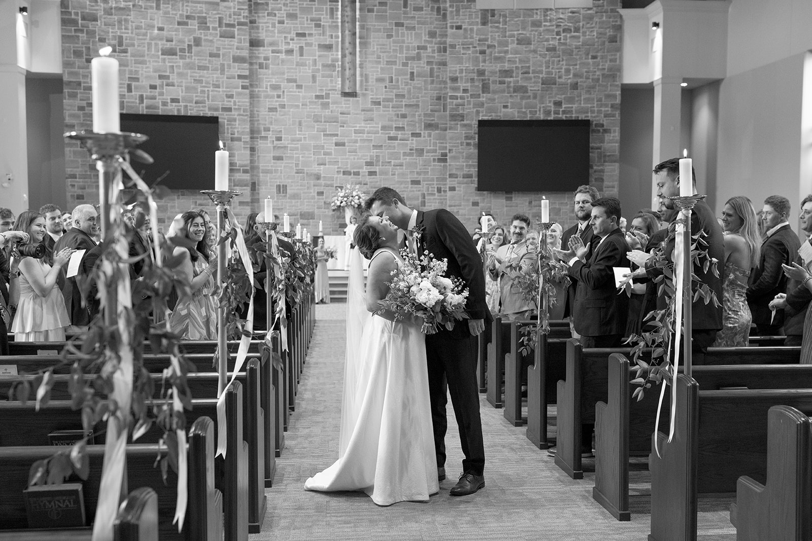 bride and groom kissing as they walk down the aisle taken by a Greenville wedding photographer