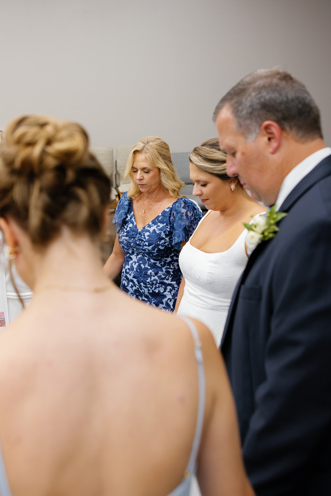 Bride stands with family and friends in a circle of prayer before walking down the aisle.