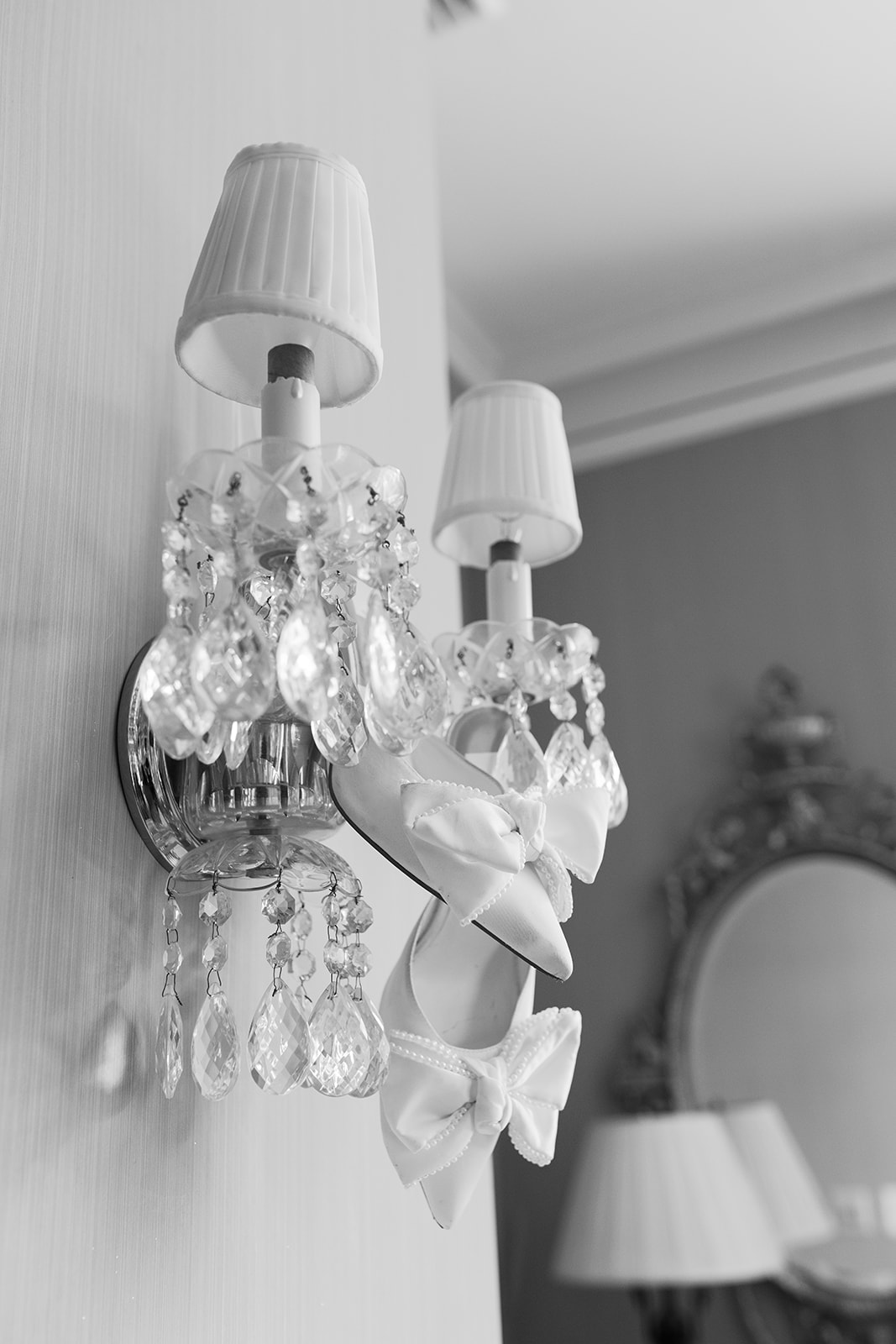 Bride’s elegant bow heels hang from a crystal wall sconce in a playful, vintage bridal detail.