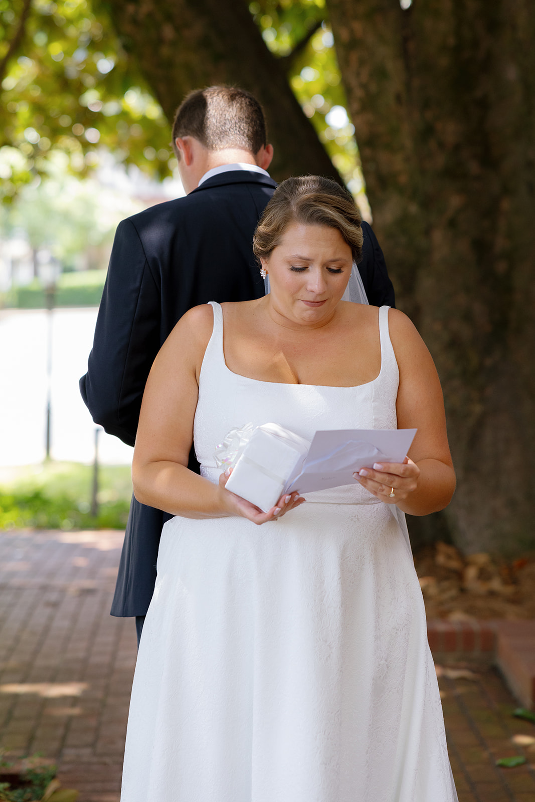 The bride reads the groom’s letter with emotion, holding a small gift during their touching first look.