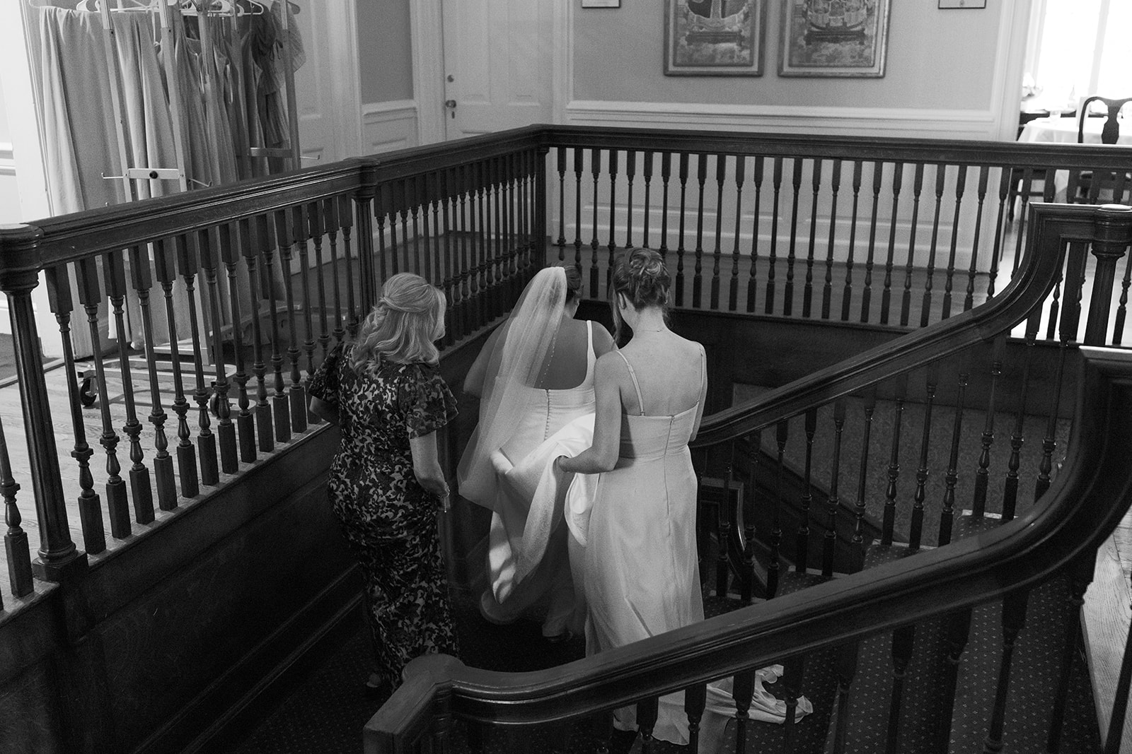 Bride descends the grand staircase with support from her mom and bridesmaid before the ceremony.