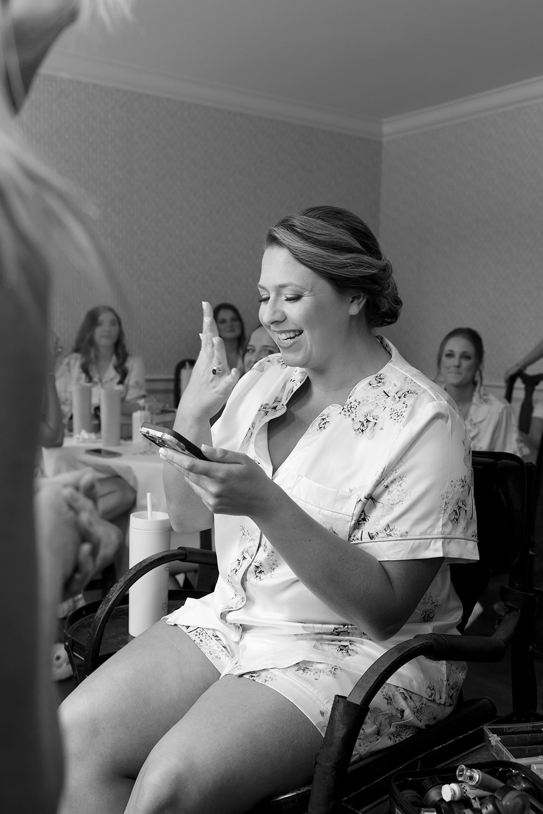 Bride laughs through happy tears while reading a message on her phone during a sweet morning moment.