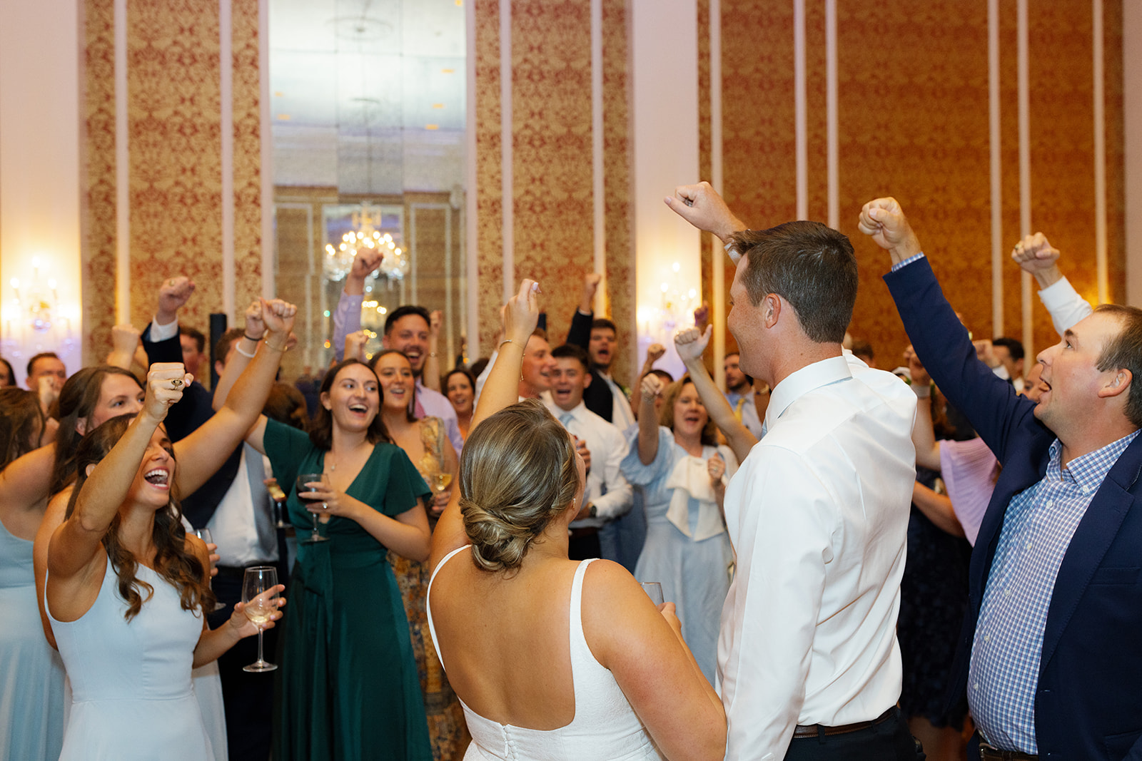 bride and groom cheering with their wedding guests