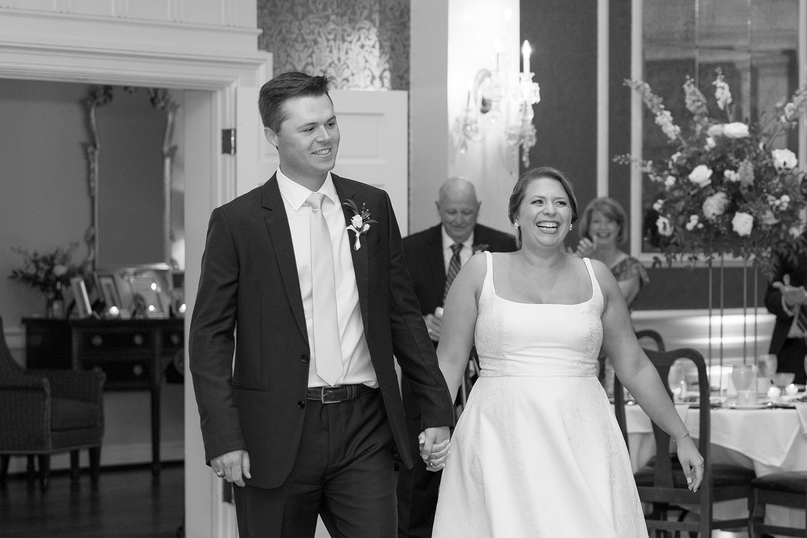 Newlyweds beam with joy as they make their grand entrance into the elegant reception space taken by a Greenville wedding photographer.