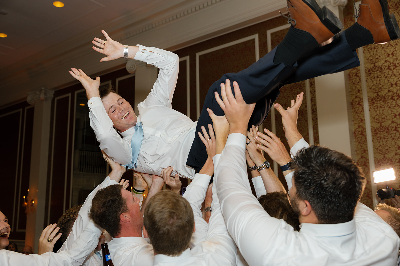 groomsmen lift the groom above their heads as the dance