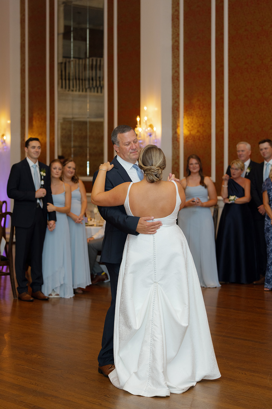 Bride and her father share a heartfelt dance as loved ones watch with emotion.