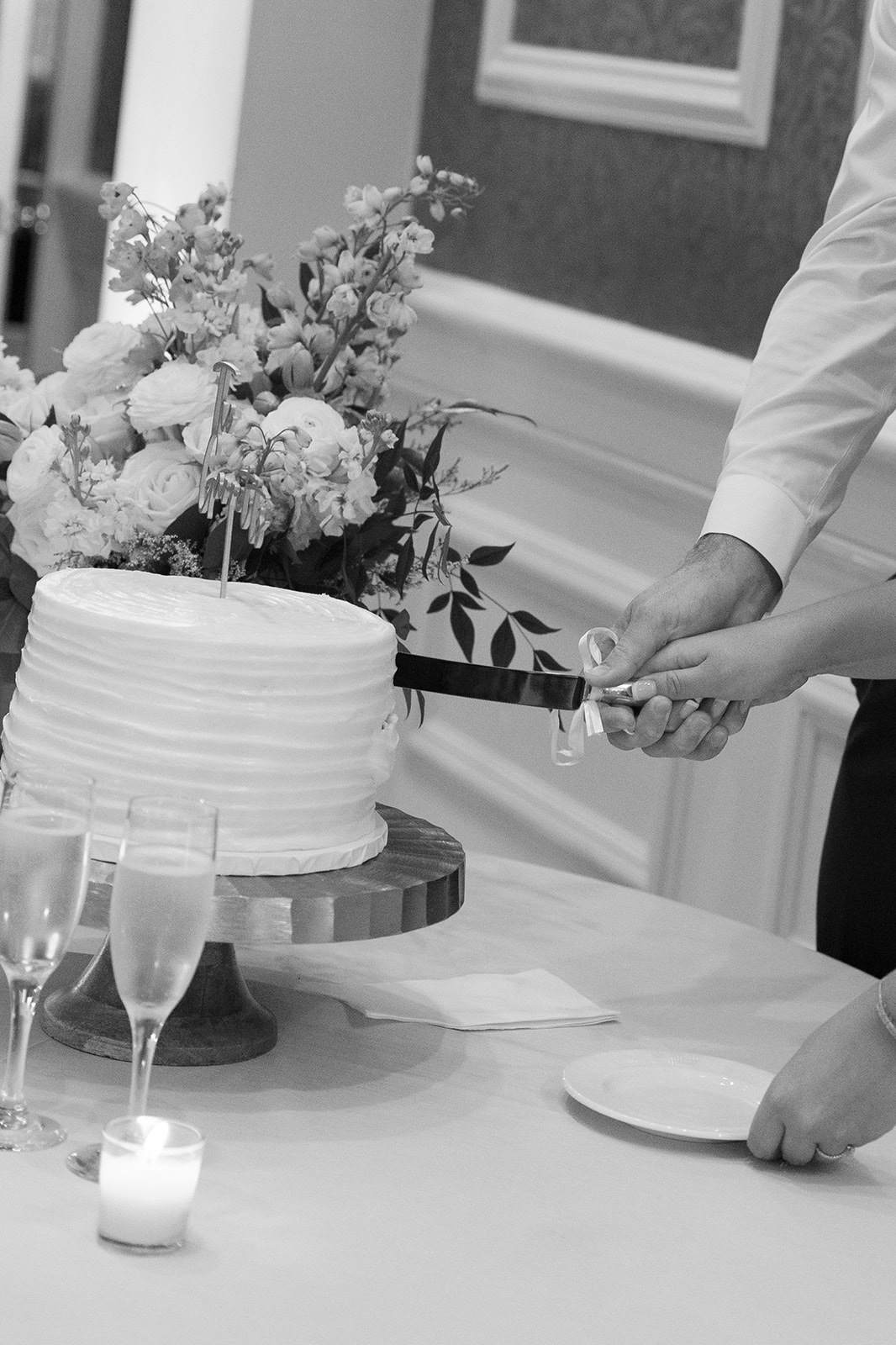 Hands clasped, the couple cuts their cake surrounded by soft candlelight and florals.