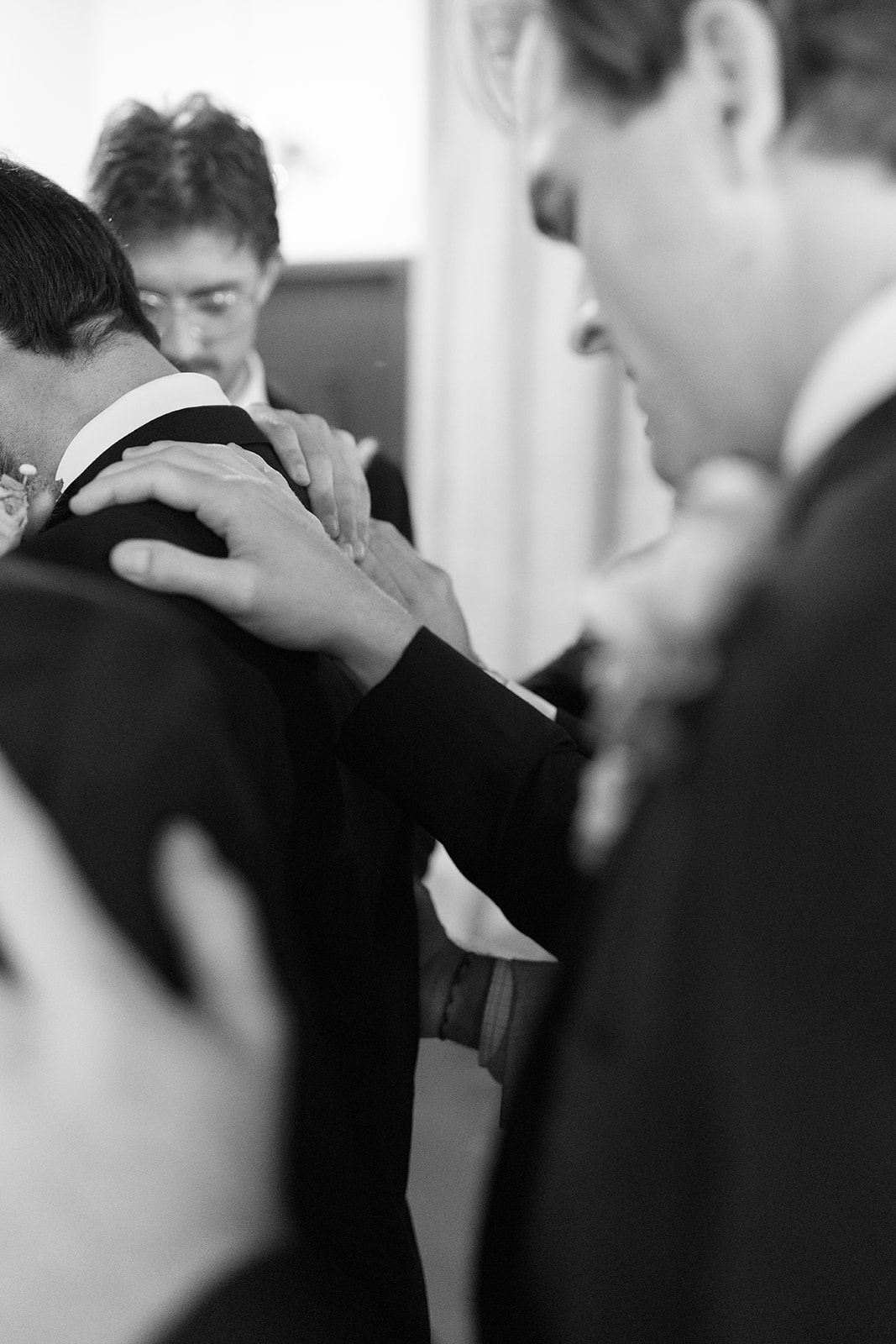 groomsmen putting their hands on the groom for a prayer before his Greenville wedding