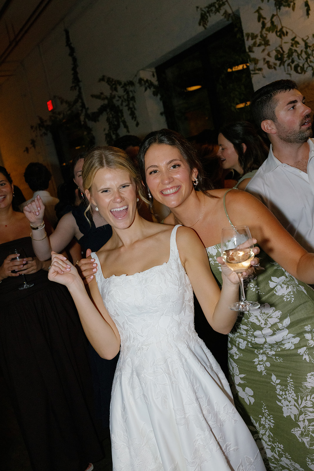 Bride and a bridesmaid smile and pose during a lively reception party.