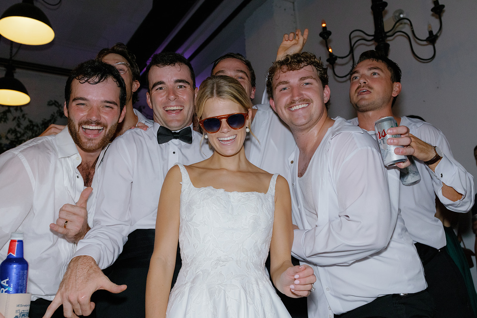 Bride in sunglasses poses with groomsmen during a fun late-night dance moment.