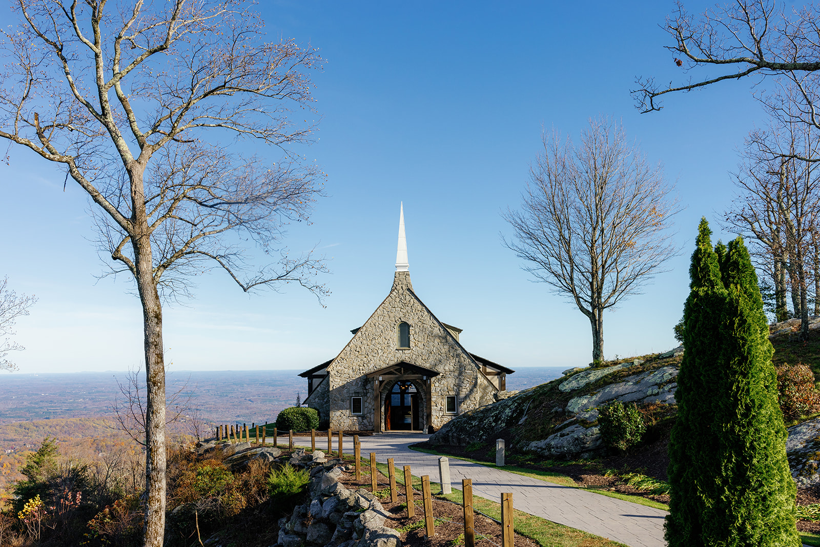 The Cliffs at Glassy Chapel sits atop a mountain ridge in South Carolina, framed by leafless trees and a bright blue sky.