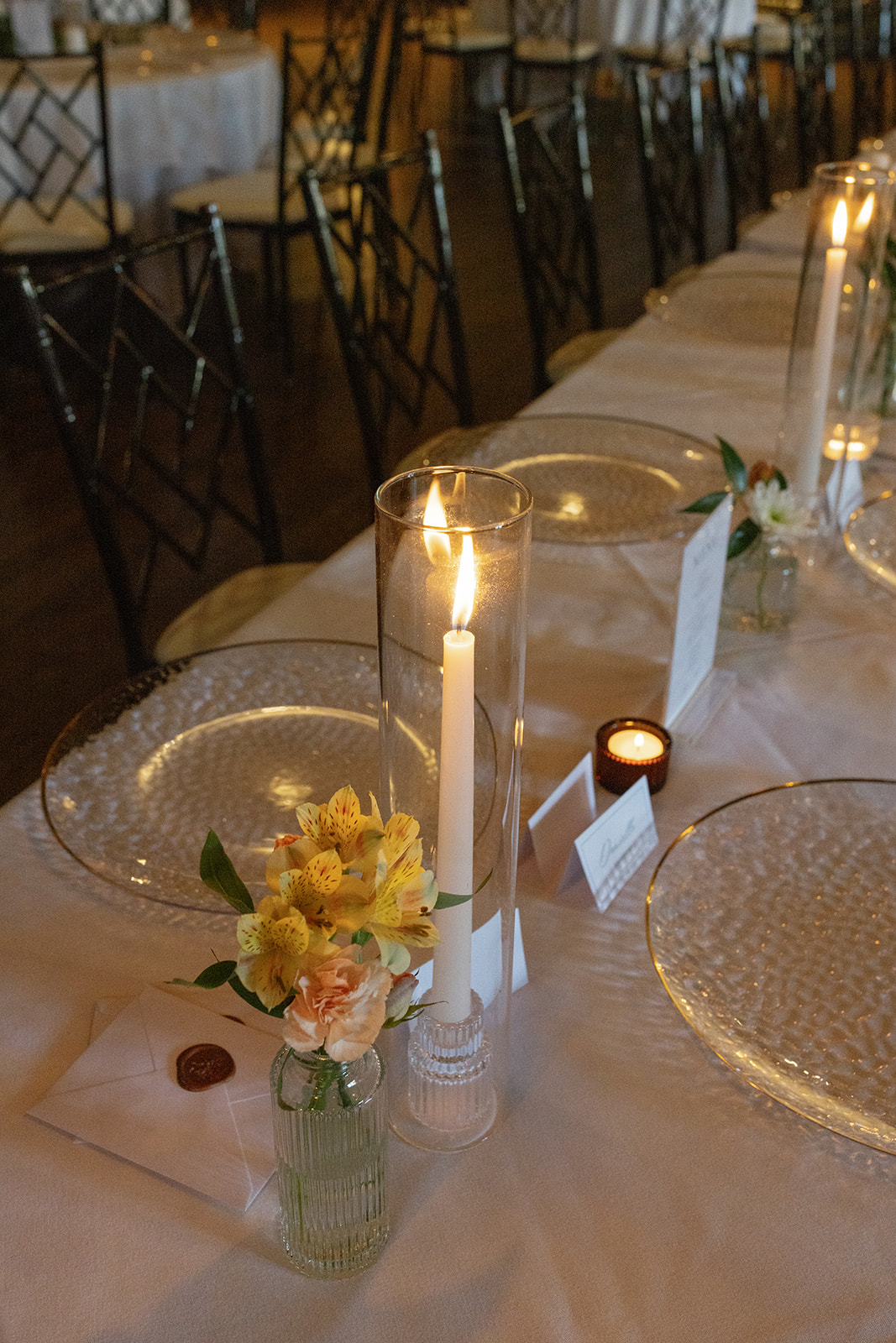 A timeless wedding tablescape with taper candles, florals, and delicate glass plates set for dinner.
