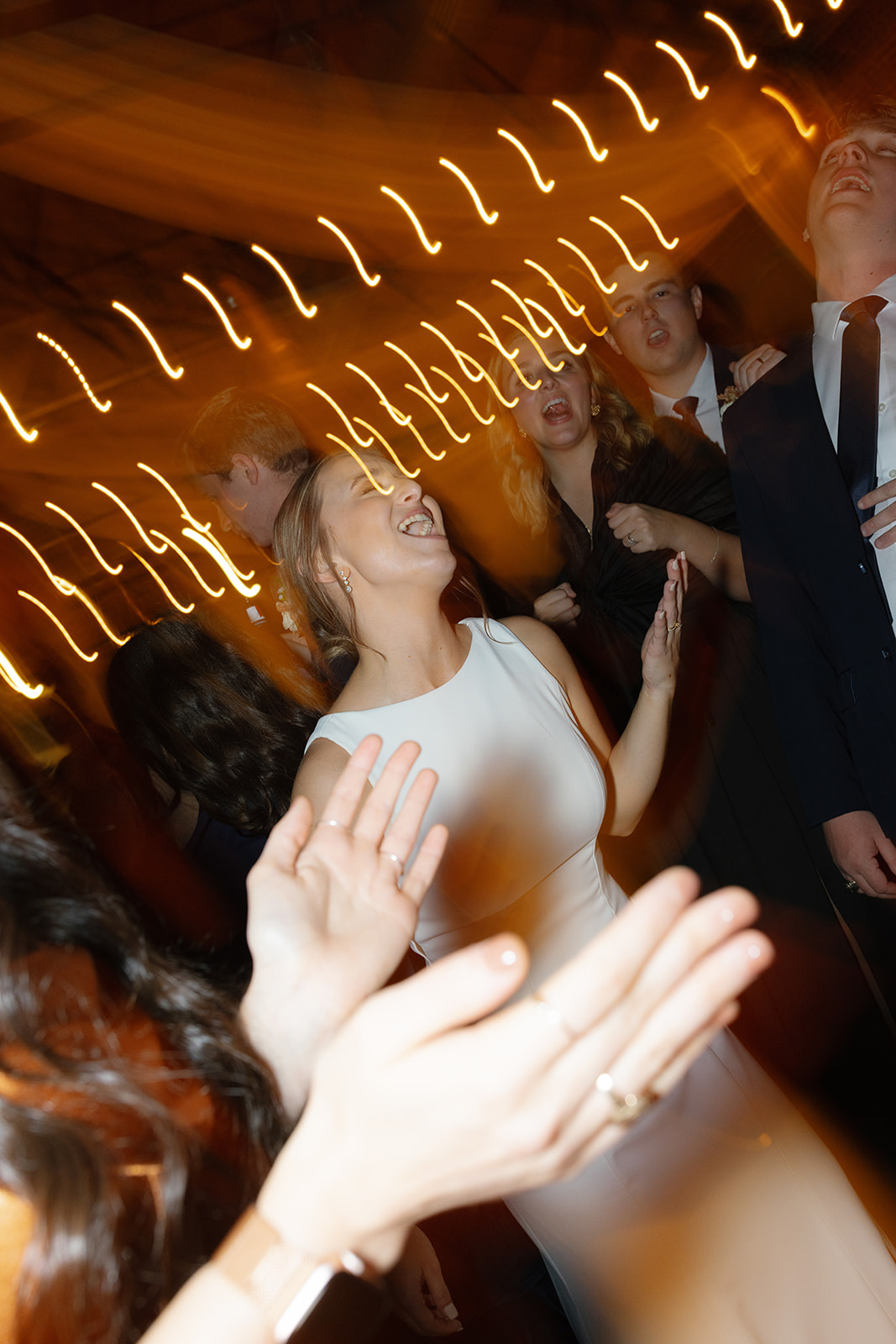 The bride sings as the dance floor fills with cheering guests.