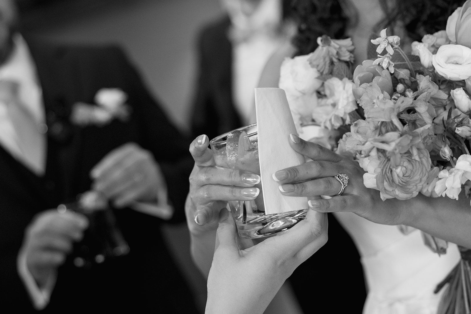 Bride accepts a celebratory cocktail while holding her colorful bouquet at the reception.