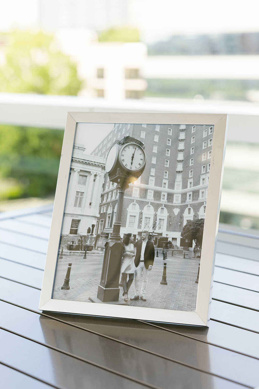 Framed black-and-white photo of the couple embracing in their engagement photo outside a classic building in downtown Greenville.