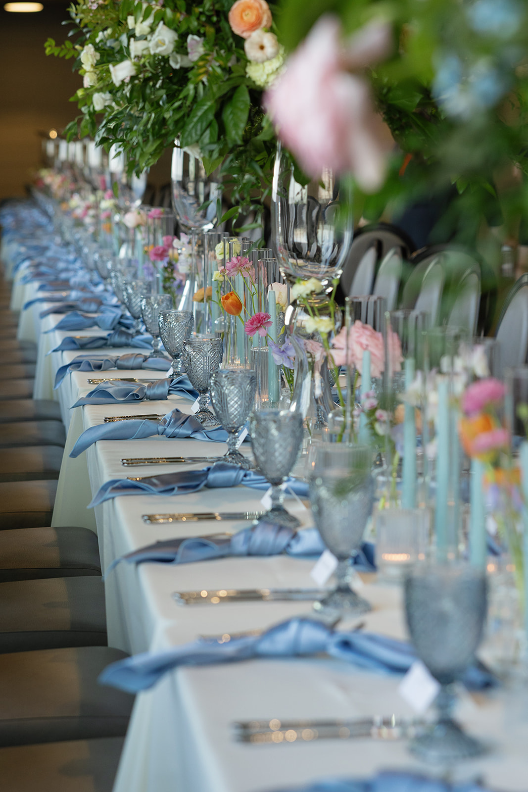 Elegant reception table with blue napkins, pastel florals, and crystal glassware at Avenue in Greenville, SC.