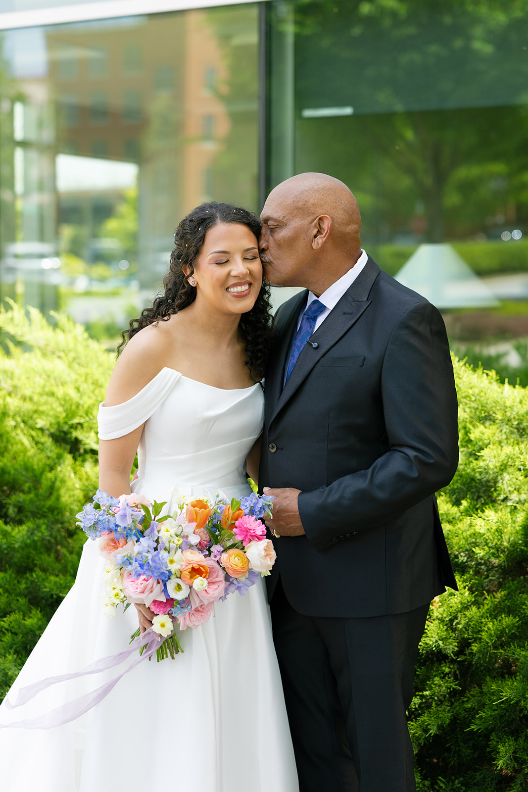 Bride beams as her father kisses her cheek during a sweet moment before the ceremony in downtown Greenville.
