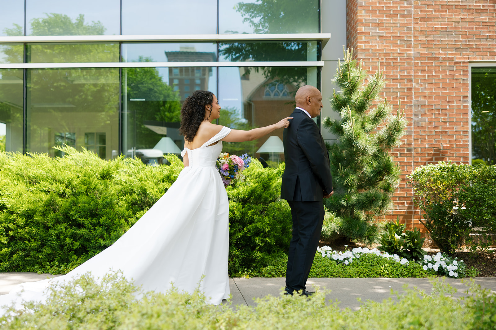 Bride reaches out to tap her father on the shoulder during an emotional first look taken by a Greenville SC Wedding Photographer..