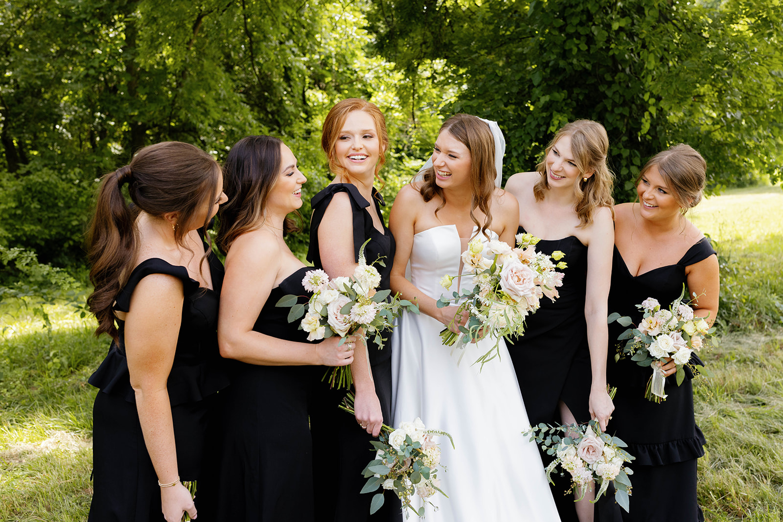 The bride and her bridesmaids laugh together during a lighthearted outdoor photo at The 405.