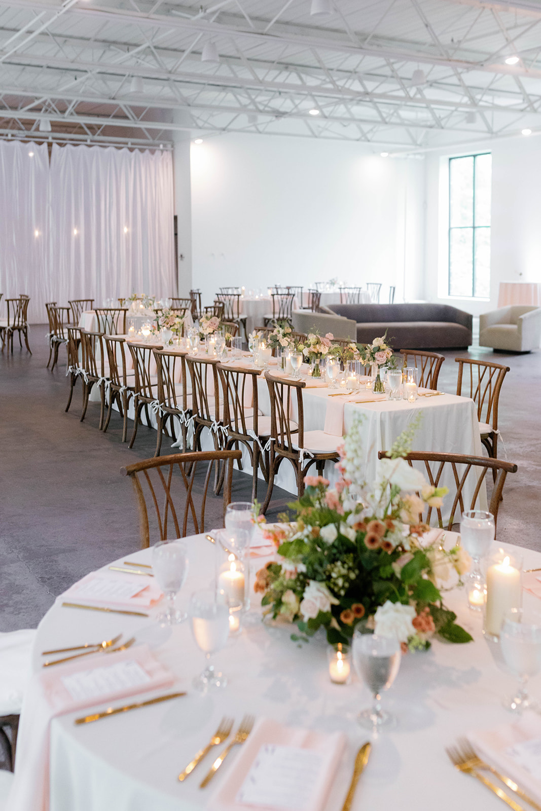 Reception space at The 405 glows with soft florals, candlelight, and long banquet-style tables.