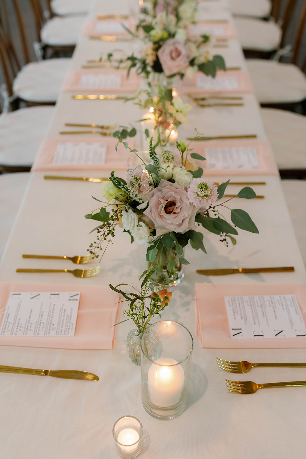 Romantic blush florals and candlelight line a reception table at a Greenville wedding venue.