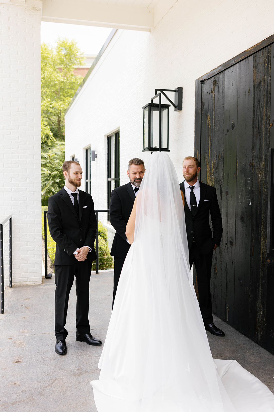 The bride shares a joyful first look moment with groomsmen outside The 405 in Greenville, SC.