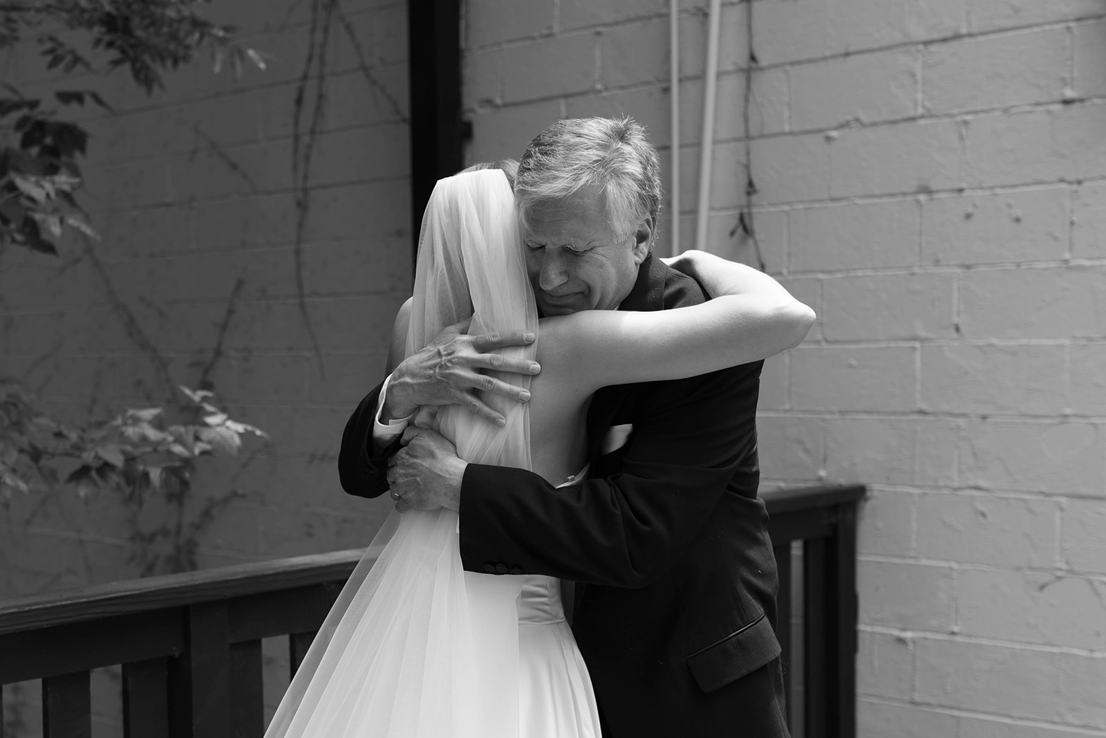 Emotional father-daughter embrace on the deck outside The 405, a romantic Greenville wedding venue.