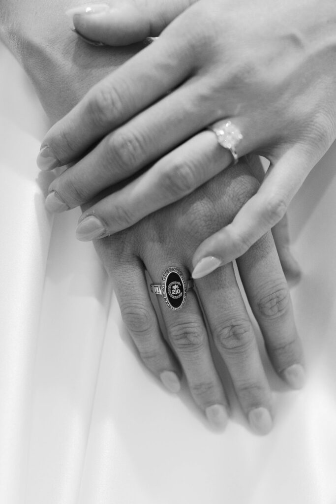 Two hands rest together, showcasing the bride’s engagement ring and a meaningful black onyx family heirloom.