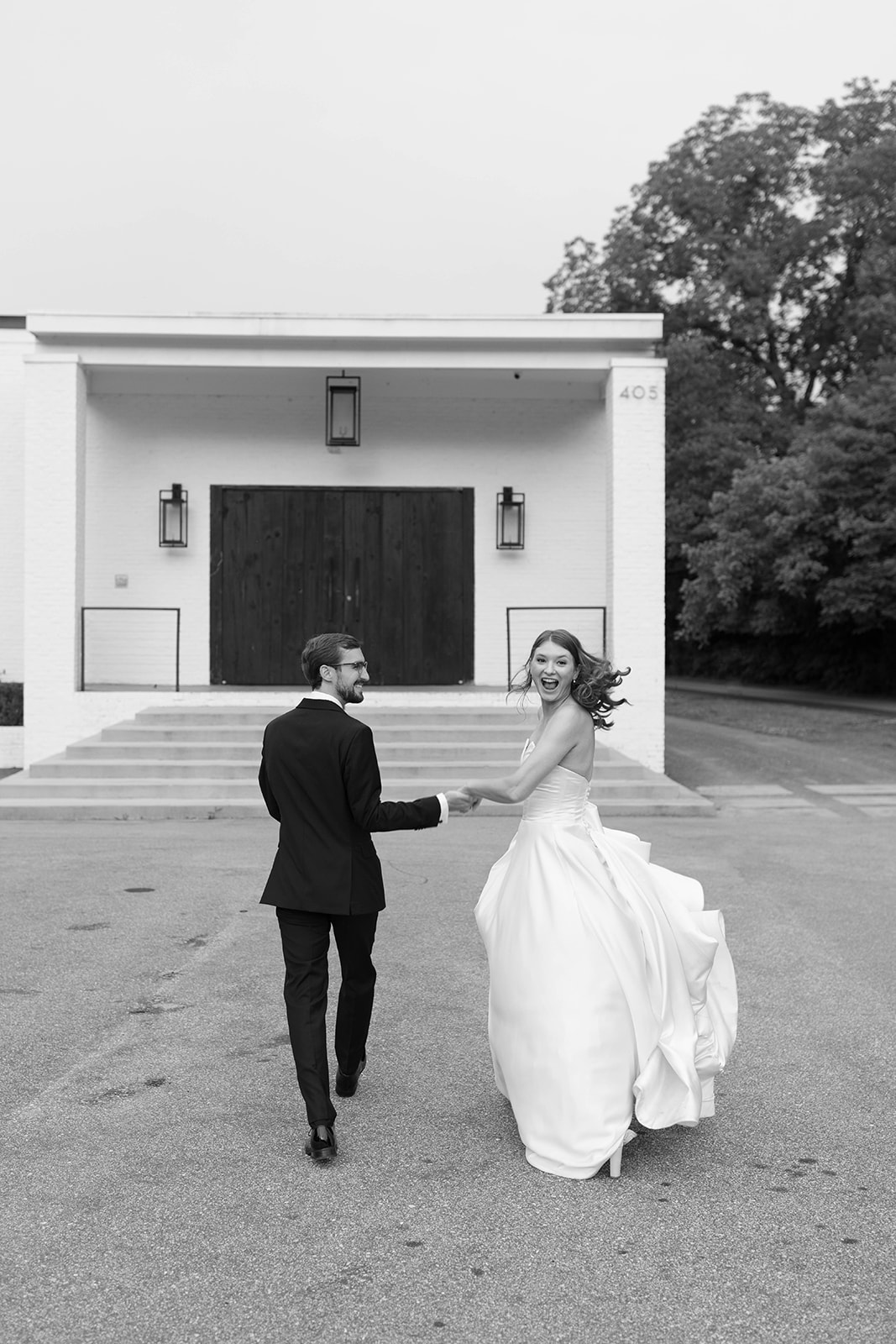 Newlyweds laugh and hold hands while walking away from their ceremony at The 405 in Greenville, SC.