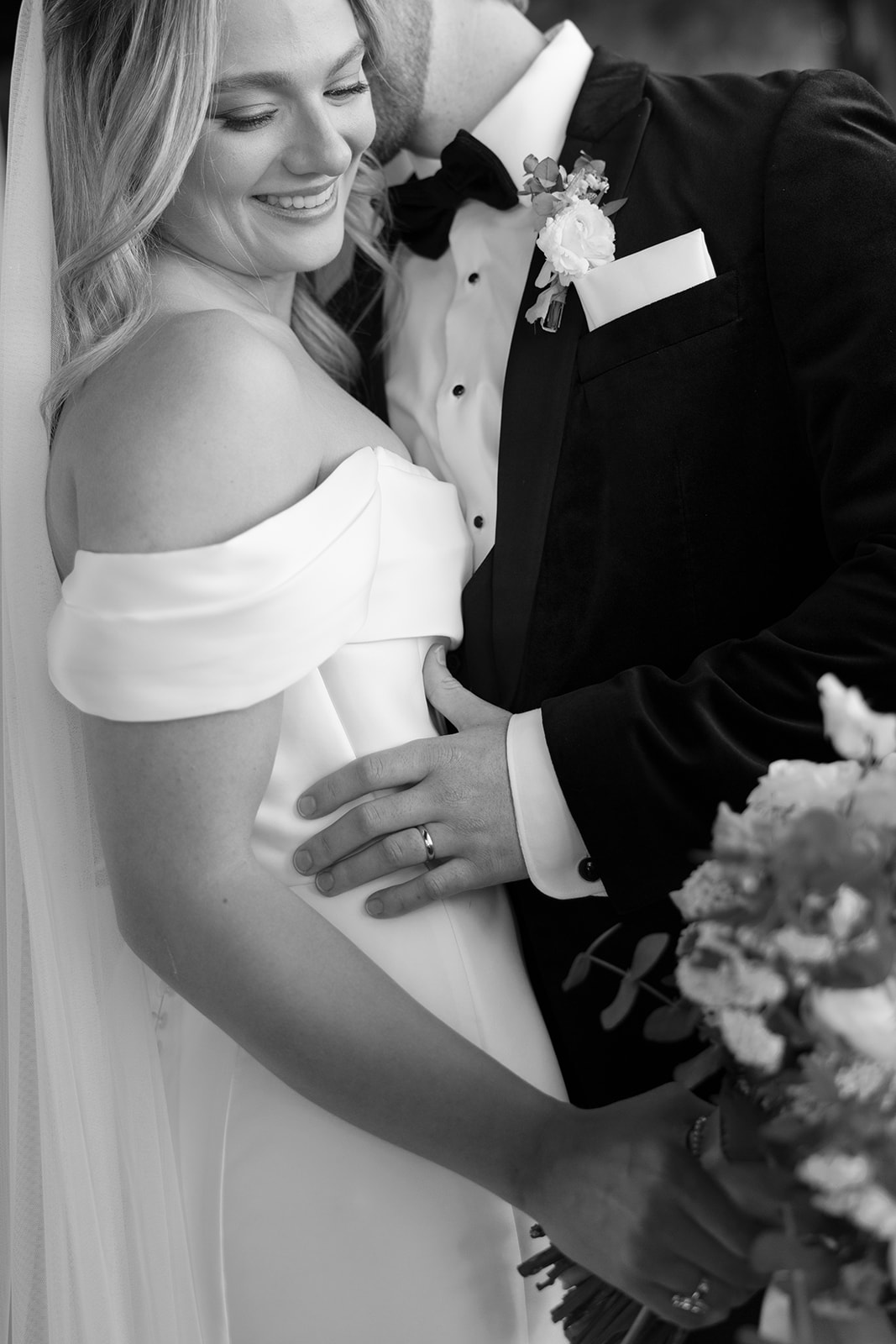 bride smiling while groom kisses her cheek