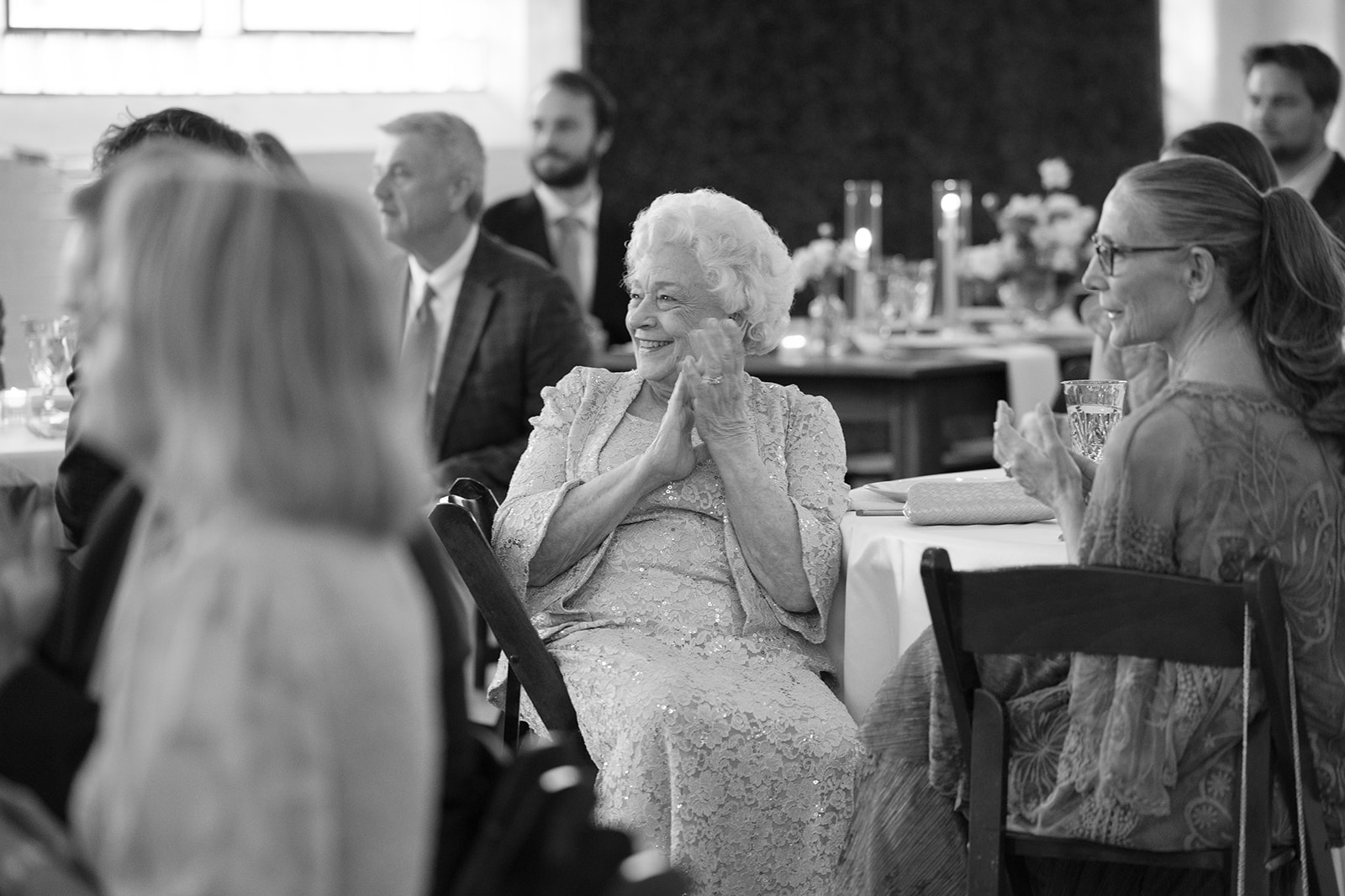a sweet grandma claps along with other wedding guests as bride and groom makes their entrance