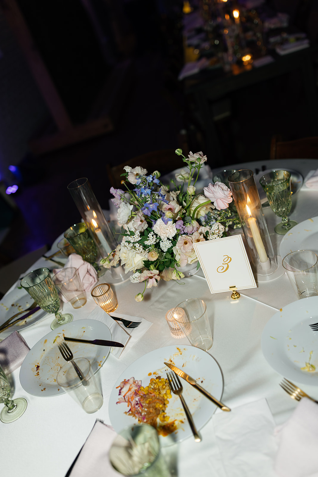 Candlelit table with floral centerpieces and empty plates at timeless wedding 