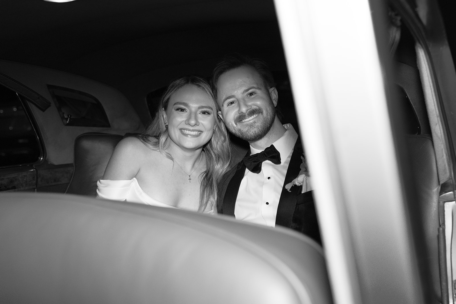 bride and groom smiling in the back of their getaway car taken by a wedding photographer in South Carolina.