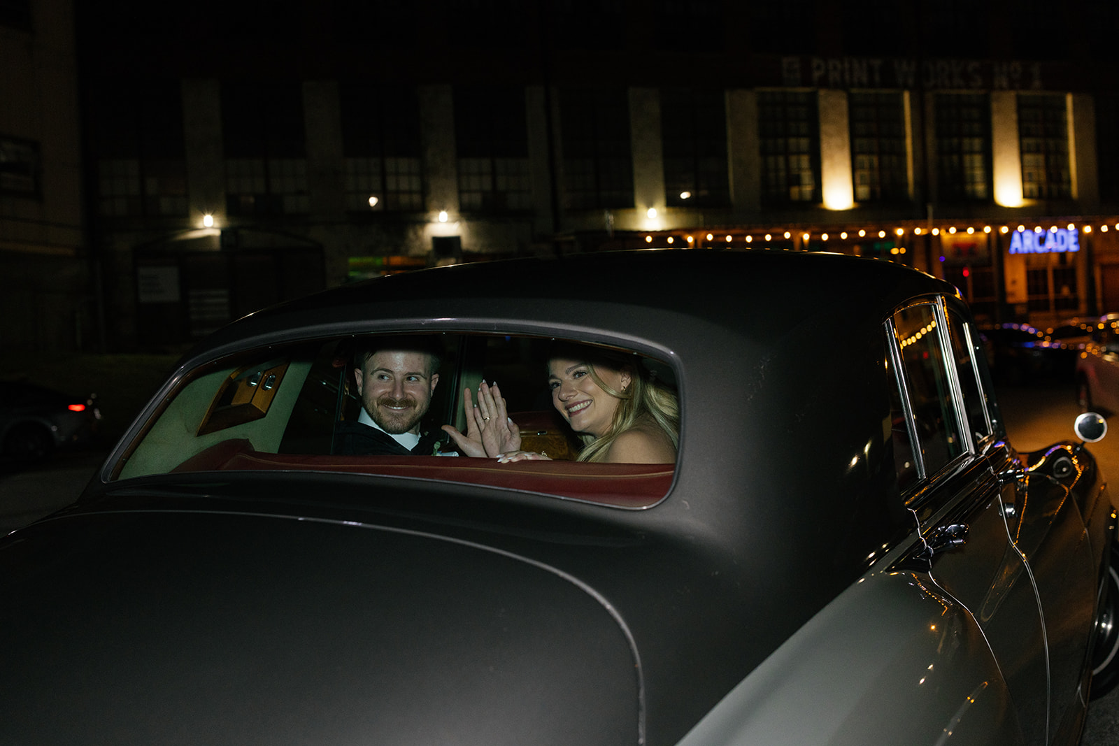 bride and groom waving goodbye in their getaway car taken by a wedding photographer in South Carolina.
